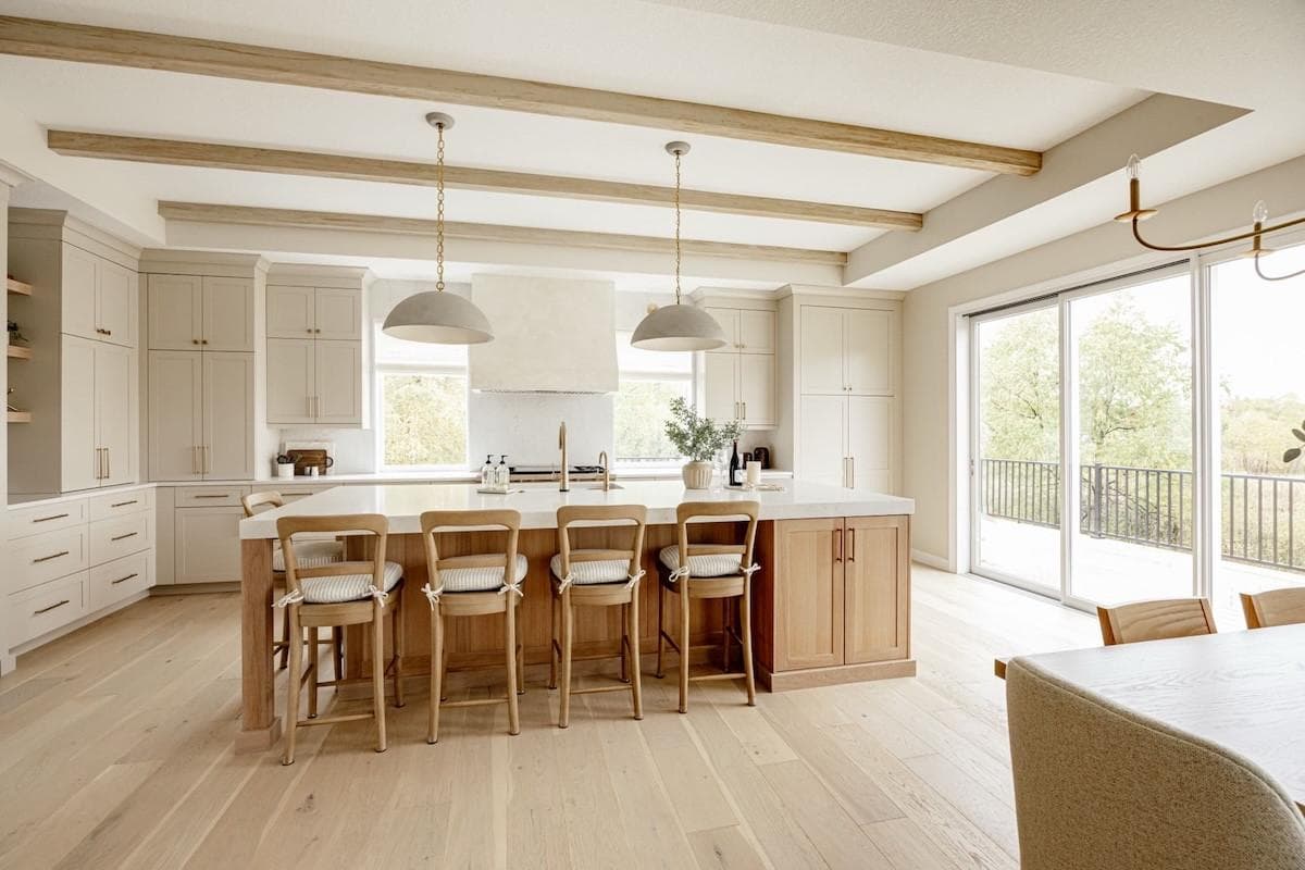 A bright kitchen with exposed ceiling beams and a large island with bar stools